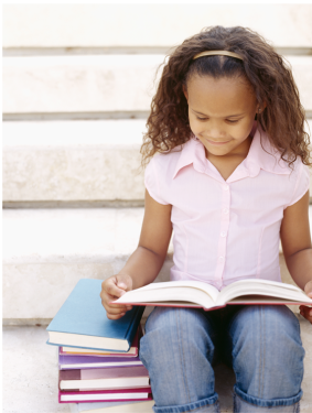 Young girl smiling reading a book.